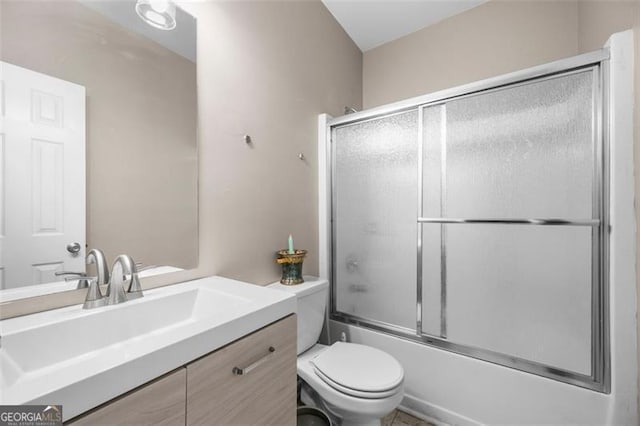 full bathroom with vanity, bath / shower combo with glass door, and toilet