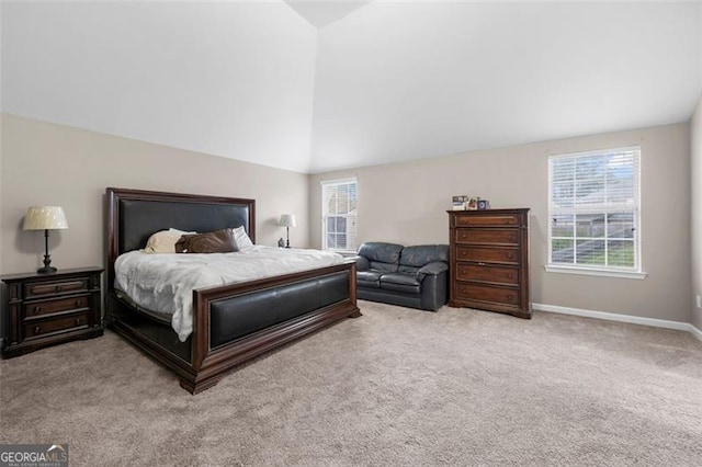 bedroom with multiple windows, lofted ceiling, and light colored carpet