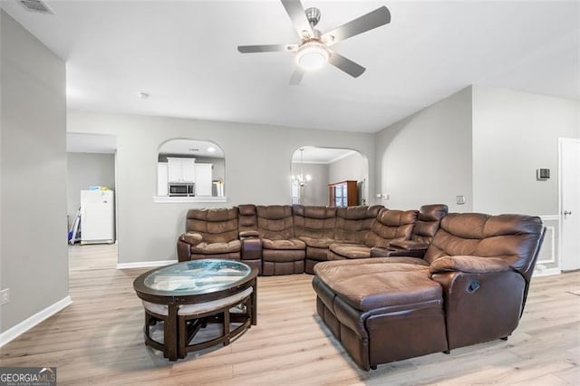 living room with ceiling fan with notable chandelier and light hardwood / wood-style floors