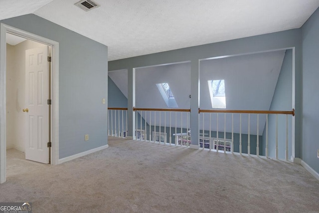 empty room featuring light carpet and lofted ceiling with skylight