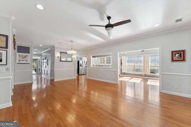 unfurnished living room featuring crown molding, ceiling fan with notable chandelier, and light hardwood / wood-style flooring