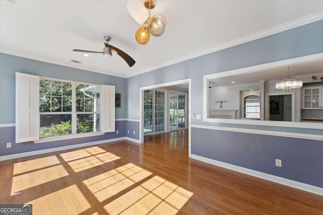 unfurnished living room featuring hardwood / wood-style floors, ceiling fan with notable chandelier, and ornamental molding