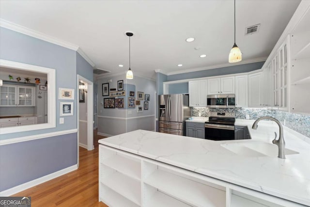 kitchen with stainless steel appliances, white cabinetry, sink, and pendant lighting