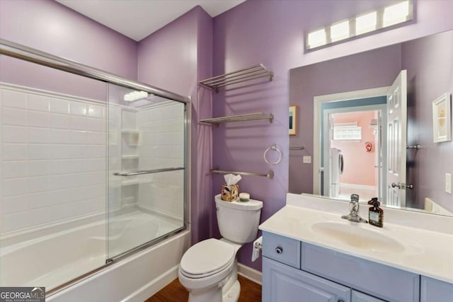 full bathroom featuring vanity, hardwood / wood-style flooring, bath / shower combo with glass door, and toilet