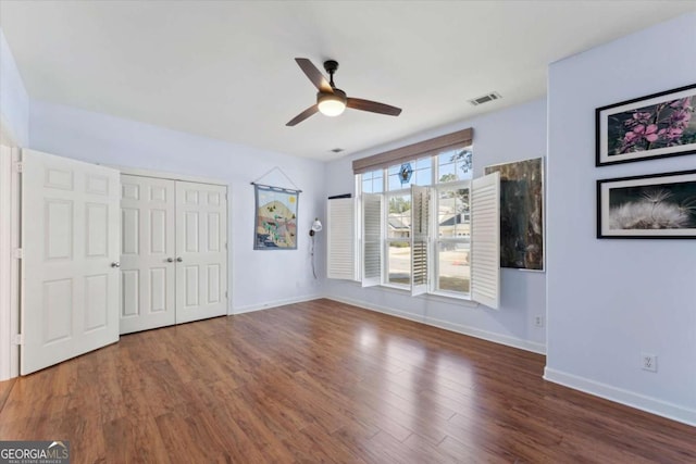 unfurnished bedroom with ceiling fan, dark hardwood / wood-style flooring, and a closet