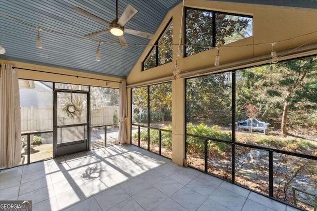 unfurnished sunroom featuring ceiling fan, a healthy amount of sunlight, and vaulted ceiling