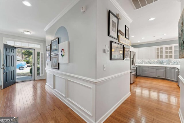 foyer entrance featuring ornamental molding and light hardwood / wood-style flooring