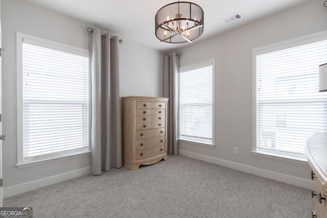 unfurnished bedroom with an inviting chandelier, light colored carpet, and multiple windows