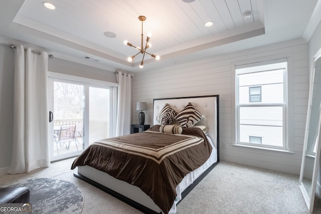 carpeted bedroom featuring multiple windows, a tray ceiling, and access to exterior