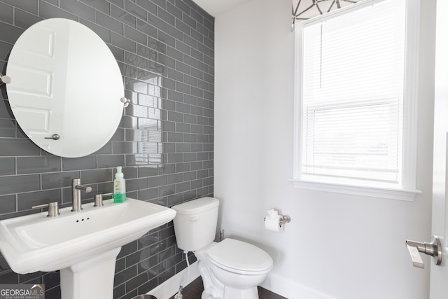 bathroom featuring tile walls, sink, and toilet