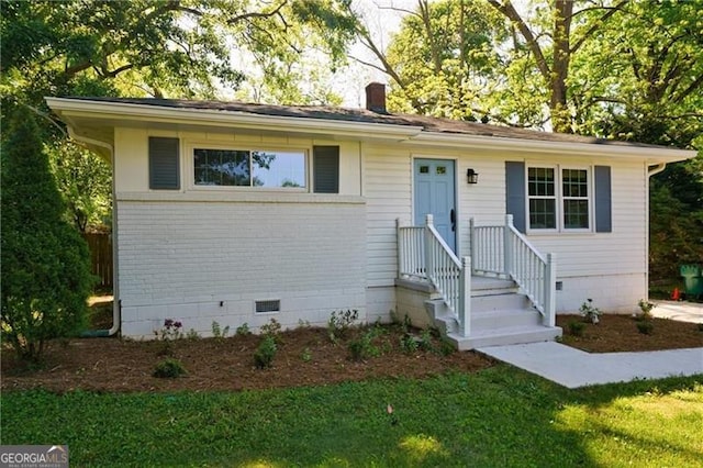 ranch-style house with crawl space, a chimney, a front lawn, and brick siding