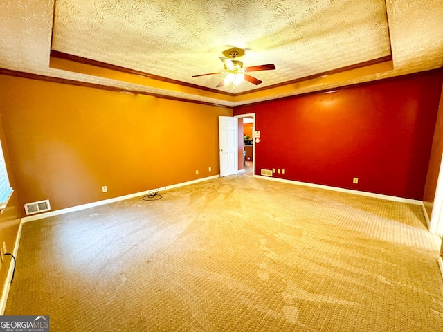 unfurnished room featuring ornamental molding, ceiling fan, a textured ceiling, and a tray ceiling