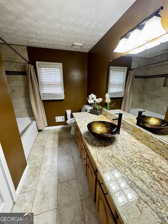 full bathroom with vanity, toilet, shower / bathtub combination with curtain, tile patterned floors, and a textured ceiling