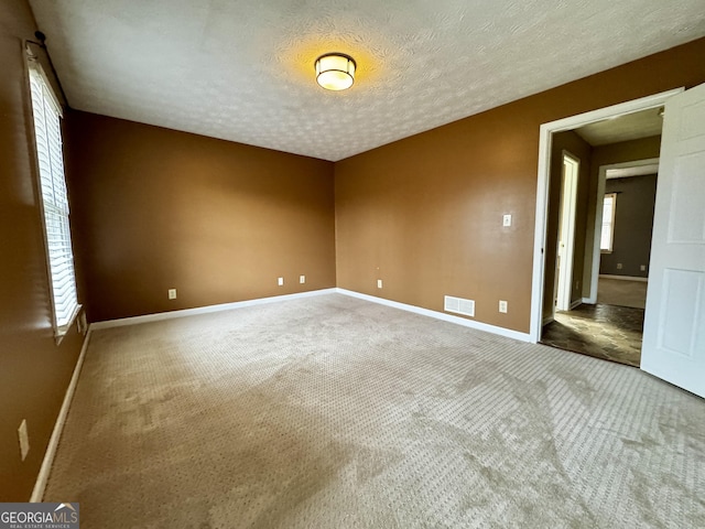 spare room featuring carpet flooring and a textured ceiling