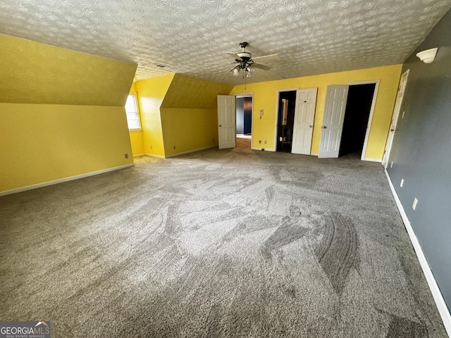 additional living space with ceiling fan, vaulted ceiling, a textured ceiling, and carpet