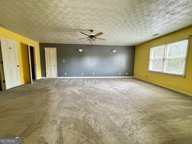 empty room with ceiling fan, carpet floors, and a textured ceiling