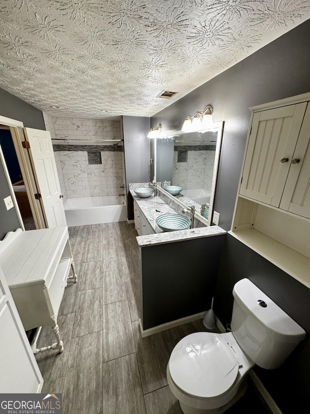 bathroom with vanity, toilet, and a textured ceiling