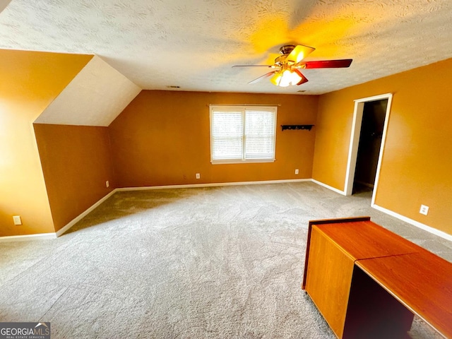 additional living space with ceiling fan, vaulted ceiling, carpet flooring, and a textured ceiling