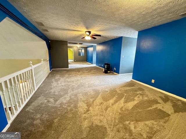 spare room with a textured ceiling, ceiling fan, and carpet