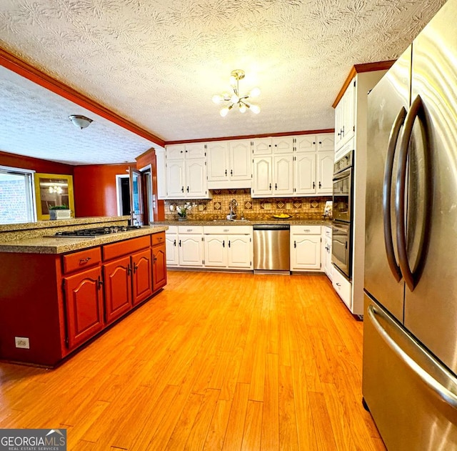 kitchen featuring sink, white cabinetry, appliances with stainless steel finishes, kitchen peninsula, and light hardwood / wood-style floors