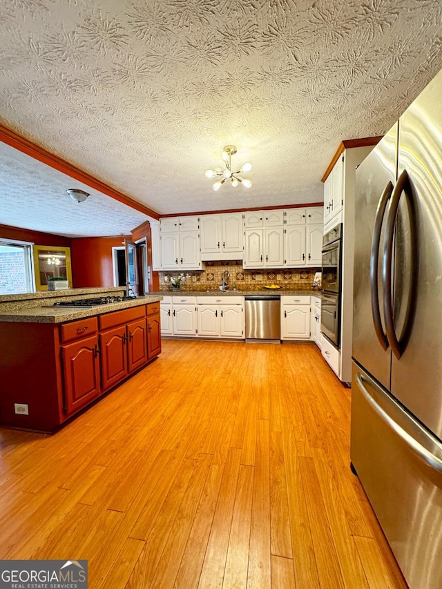 kitchen with sink, a chandelier, light hardwood / wood-style flooring, stainless steel appliances, and white cabinets