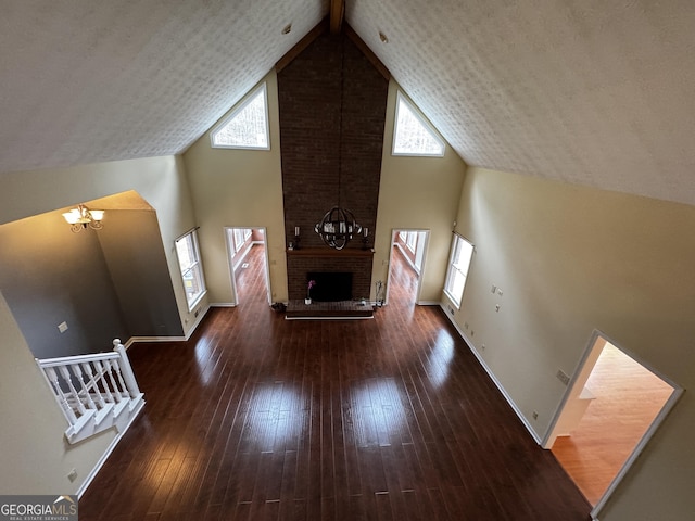 interior space featuring a healthy amount of sunlight, a brick fireplace, dark wood-type flooring, and a chandelier