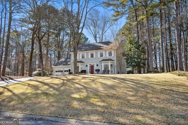 colonial inspired home with a front lawn and a garage