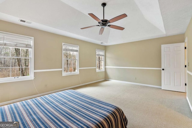 unfurnished bedroom featuring carpet, ceiling fan, and a tray ceiling