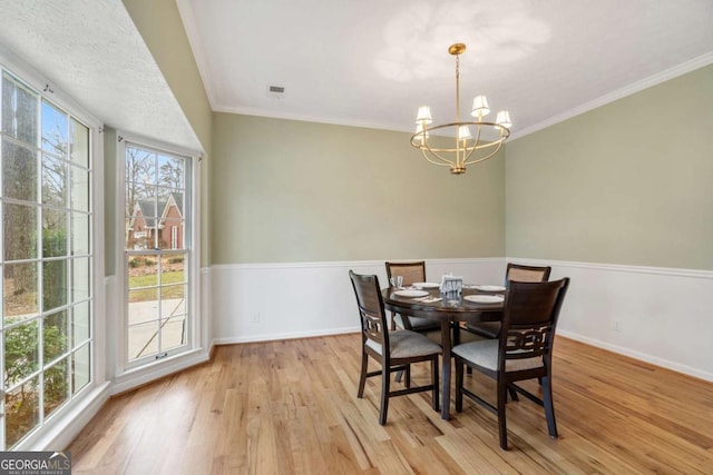 dining area with ornamental molding, a chandelier, and light hardwood / wood-style flooring