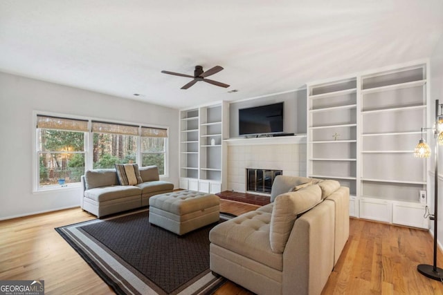 living room with light hardwood / wood-style floors, ceiling fan, and a fireplace