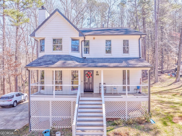 view of front of home with stairway, covered porch, driveway, and a chimney