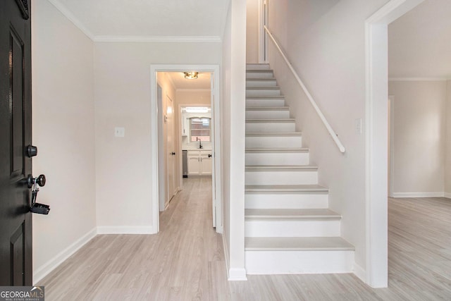 stairway featuring hardwood / wood-style flooring, ornamental molding, and sink