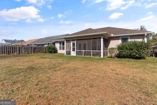 rear view of property featuring a lawn and a sunroom