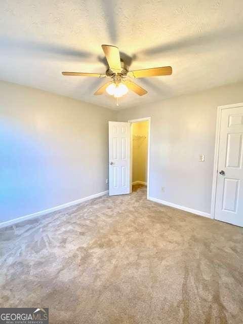 unfurnished room featuring ceiling fan, carpet floors, and a textured ceiling