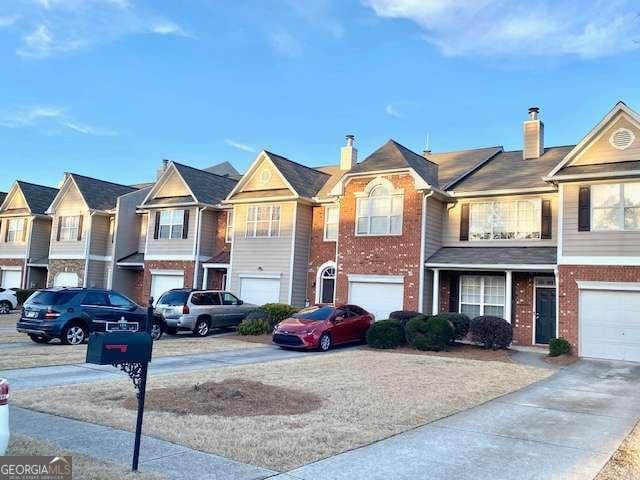 view of front of home featuring a garage, driveway, brick siding, and a residential view