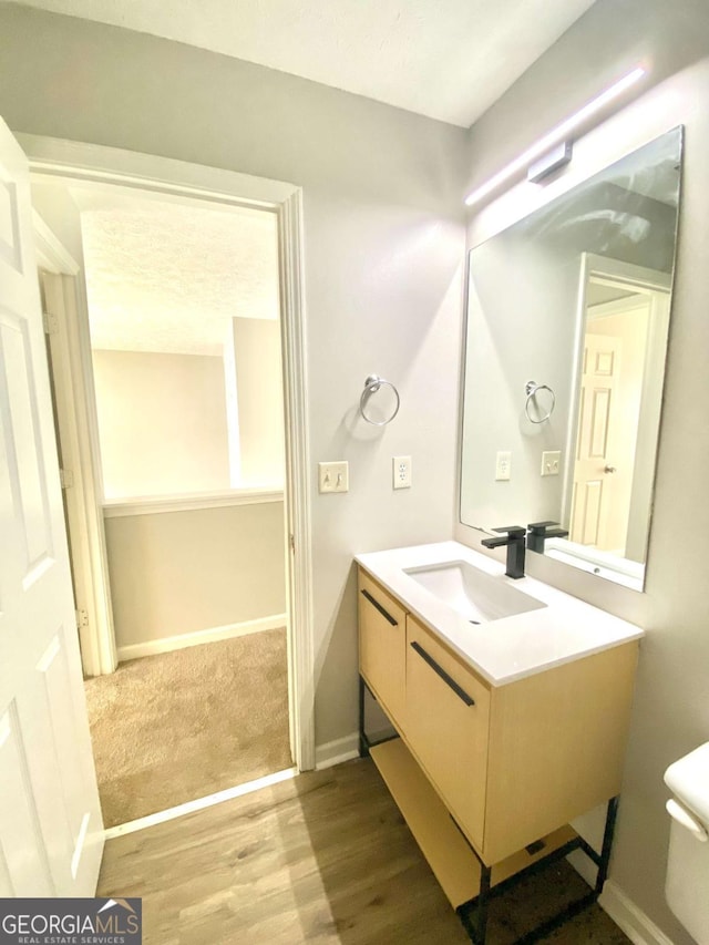 bathroom with hardwood / wood-style flooring, vanity, and toilet