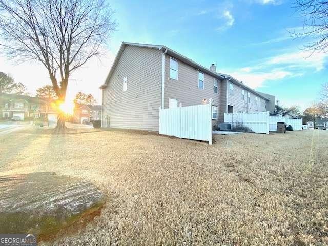 view of property exterior with cooling unit and a lawn