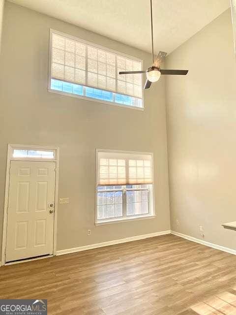 foyer with hardwood / wood-style flooring, ceiling fan, and a high ceiling