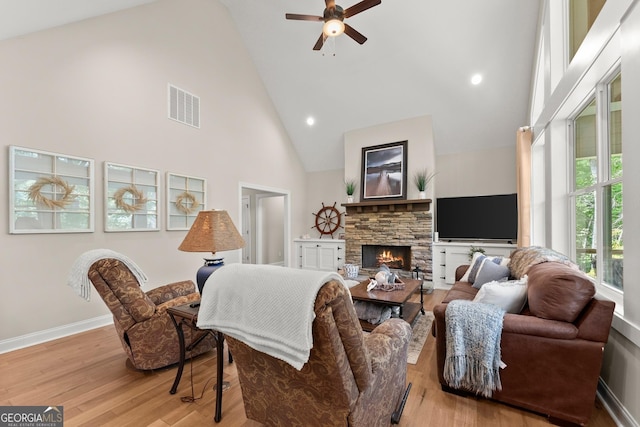 living room with ceiling fan, high vaulted ceiling, light wood-type flooring, and a fireplace