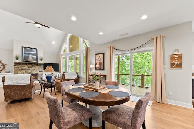 dining space featuring lofted ceiling, a fireplace, and light wood-type flooring