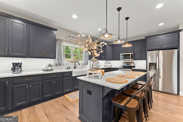 kitchen featuring sink, hanging light fixtures, a kitchen breakfast bar, a kitchen island, and stainless steel appliances