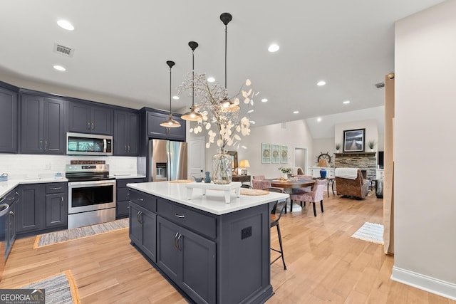 kitchen with a kitchen island, decorative light fixtures, a kitchen bar, decorative backsplash, and stainless steel appliances