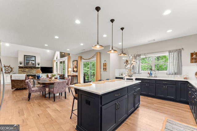 kitchen with a breakfast bar, a center island, hanging light fixtures, a fireplace, and decorative backsplash