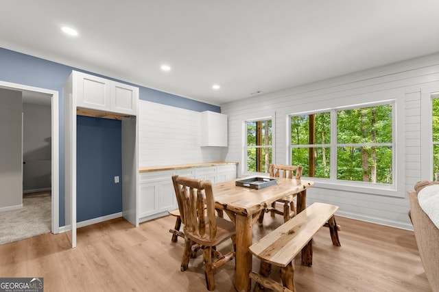 dining space featuring wooden walls and light hardwood / wood-style floors