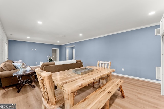 dining area with crown molding and light hardwood / wood-style floors