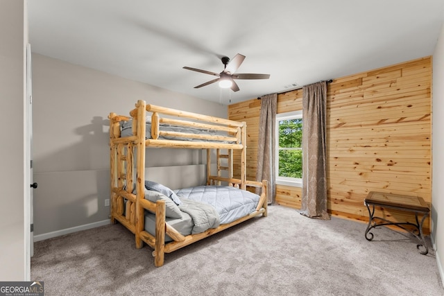 bedroom with wooden walls, ceiling fan, and carpet flooring