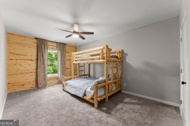 carpeted bedroom featuring ceiling fan and wooden walls