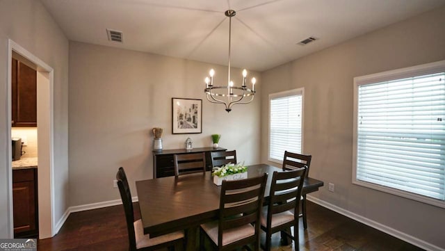 dining area with dark wood-type flooring and a chandelier