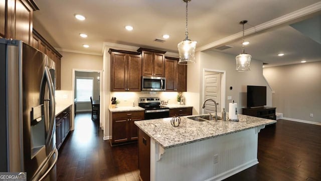 kitchen with sink, a center island with sink, pendant lighting, stainless steel appliances, and light stone countertops