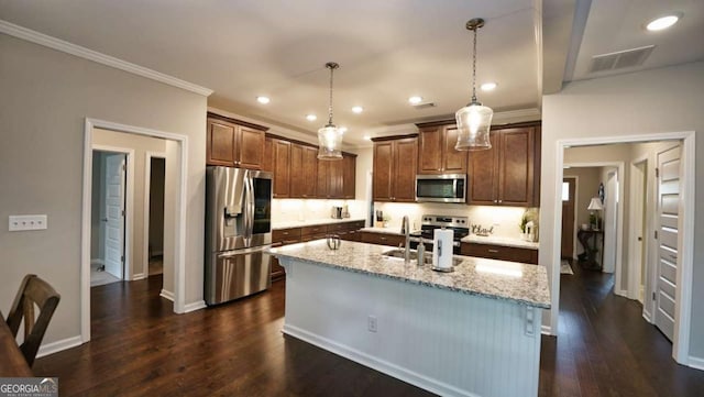 kitchen featuring appliances with stainless steel finishes, pendant lighting, sink, crown molding, and a center island with sink